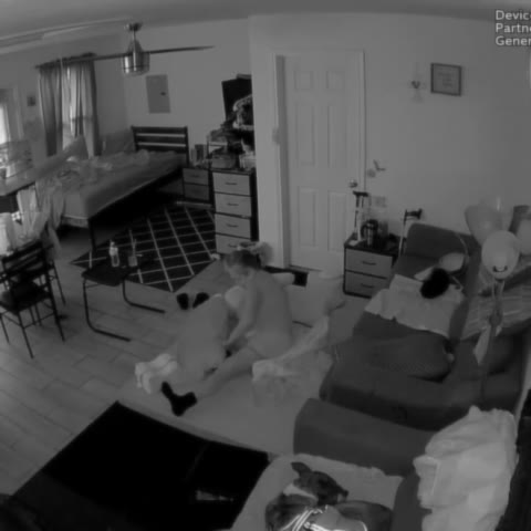 Lightly blurred benchmark Fall scene showing an older adult at floor level beside a sofa